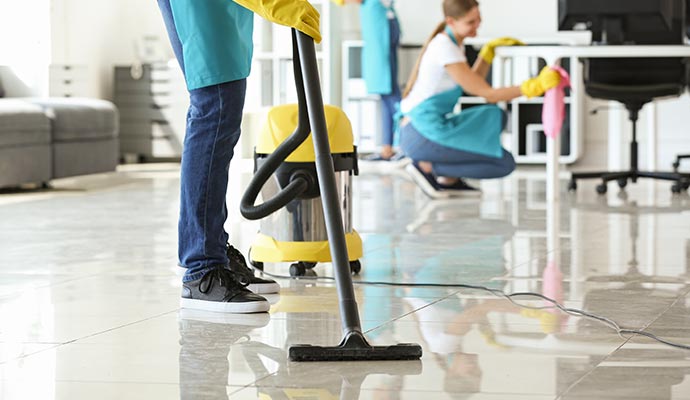 janitor hoovering floor in office building cleaning