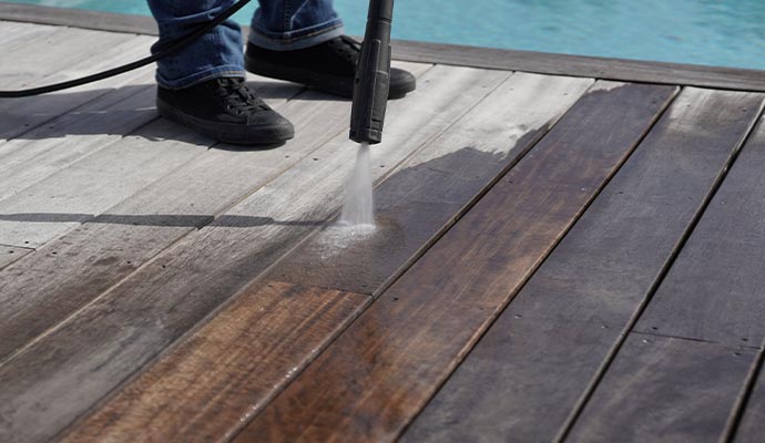 man using high pressure washer cleaning deck